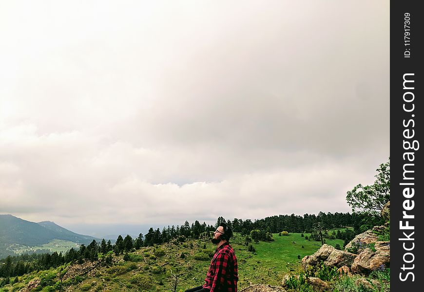 Man Wearing Red And Black Plaid Shirt Standing On Green Grass Hill