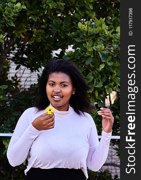 Woman in Purple Turtleneck Sweatshirt Holding Yellow Petaled Flower