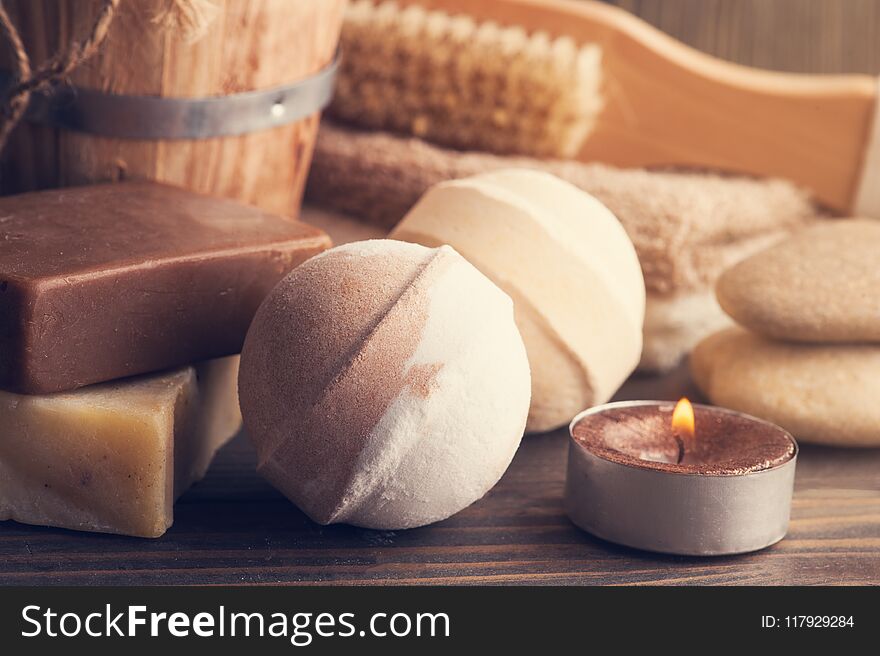 SPA composition with bath bombs, soap, lit candle. Wooden background