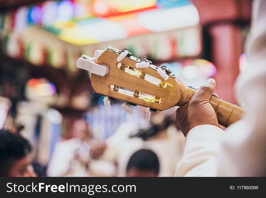 Close up of a guitar head and tuning pegs as a man is playing it in a restaurant