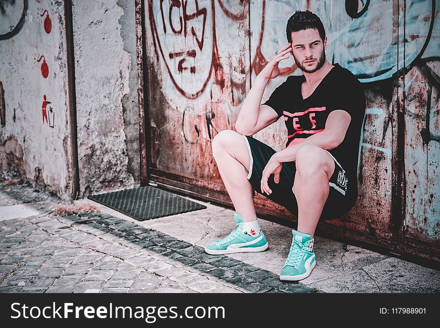 Man In Black T-shirt And Shorts Leaning on Wall