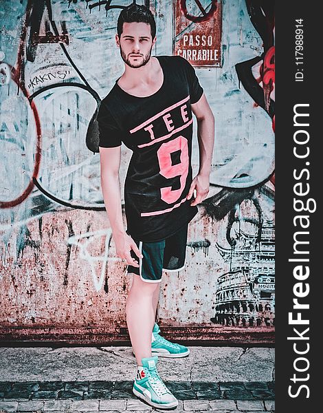Man Wearing Black and Pink Tee 9-printed T-shirt in Front of Wall