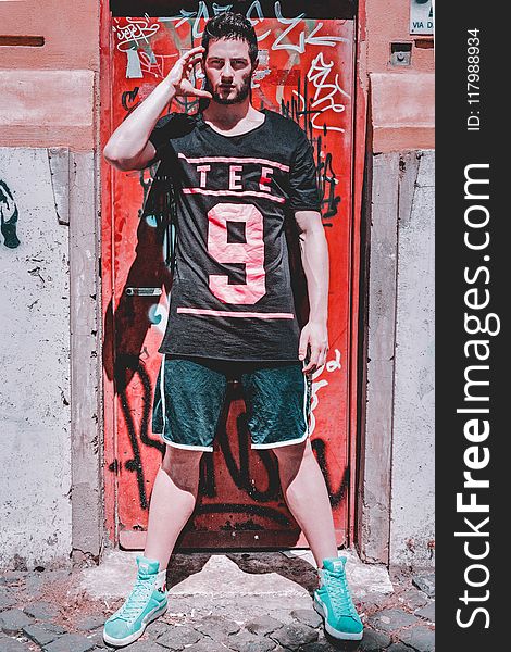 Man Wearing Black T-shirt Standing Near Red Metal Door