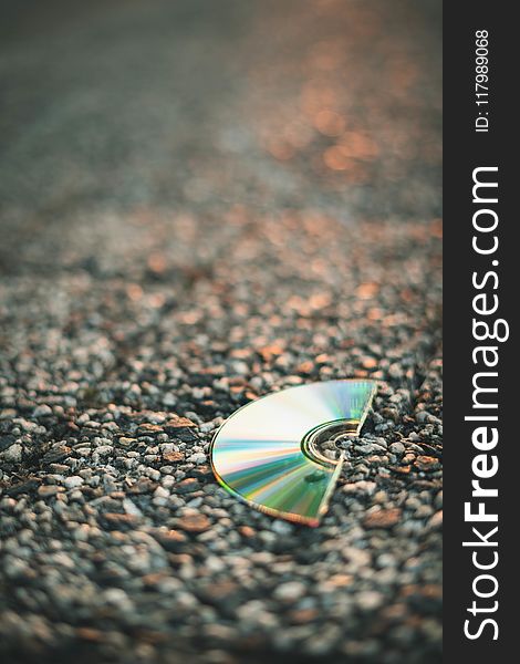 Selective Focus Photography Of Half Cut Compact Disc On Gray Pavement