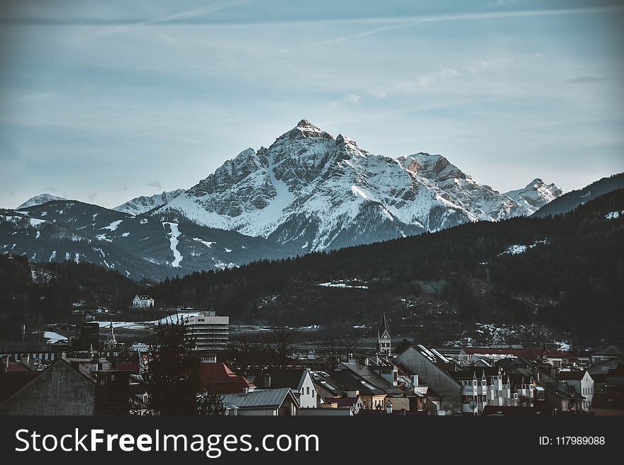 Snow Covered Mountain Near Village Under Blue Sky