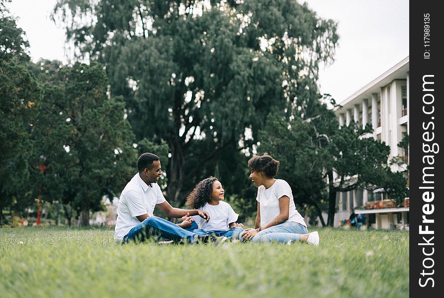 Family Sitting on Grass Near Building