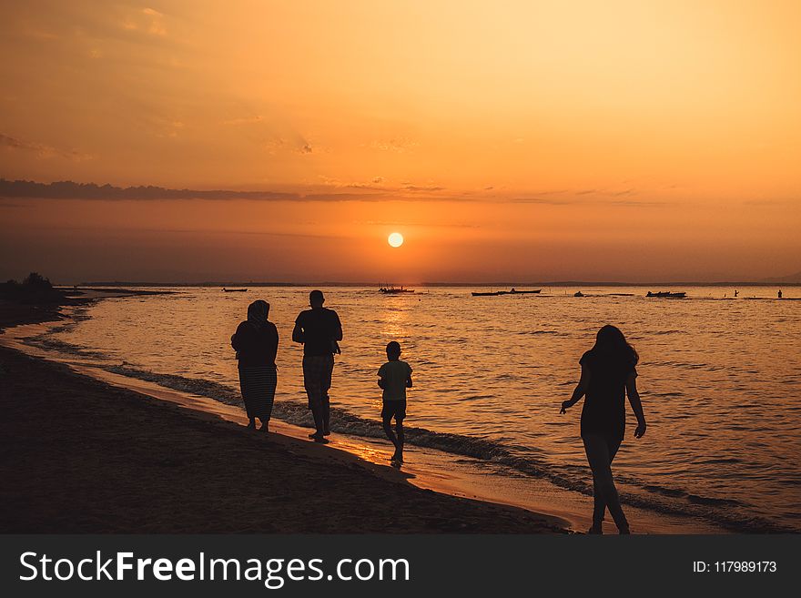Silhouette Of People Walking On Seashore During Sunset
