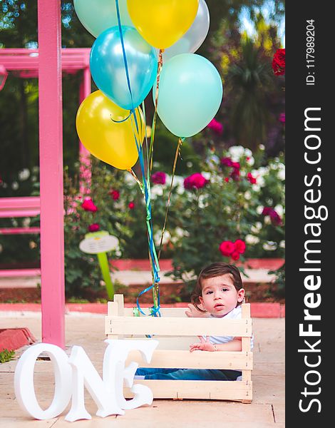 Child Wearing White Polo Shirt on Beige Wooden Crate at Daytime