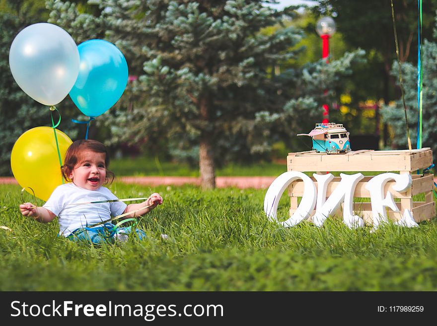 Girl Holding Blue and Yellow Balloons