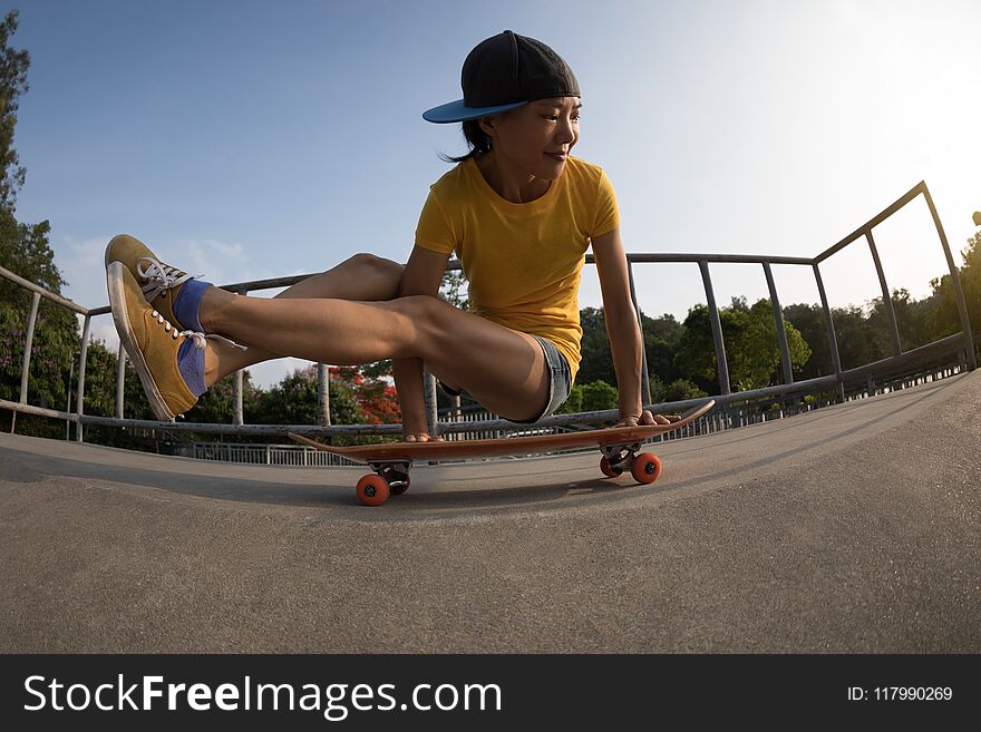 woman practicing yoga Bakasana Crane Pose on skateboard at skatepark ramp