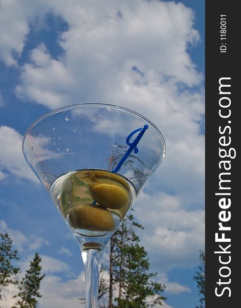 Martini with olives against the backdrop of a partly cloudy blue sky. Martini with olives against the backdrop of a partly cloudy blue sky