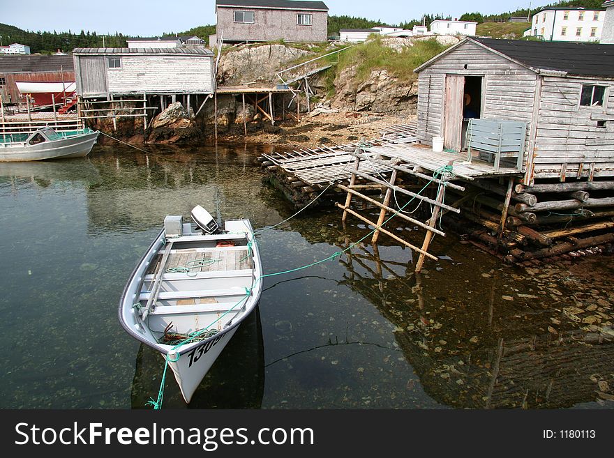 Boat tied off to dock. Typical view of outport in Newfoundland, Canada. Communities survived off the bounty of the sea for centuries. Boat tied off to dock. Typical view of outport in Newfoundland, Canada. Communities survived off the bounty of the sea for centuries.