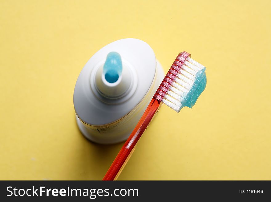 Red toothbrush with tube of thoothpaste on yellow background. Red toothbrush with tube of thoothpaste on yellow background.