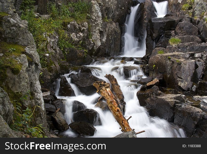 A waterfall surrounded by foliage and granite. A waterfall surrounded by foliage and granite