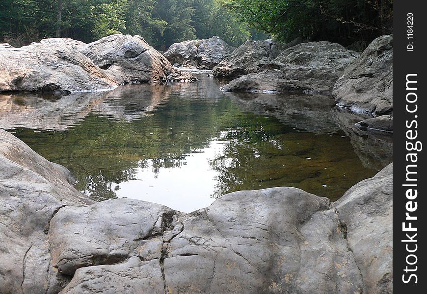 A rocky stream flowing to a small pool of water. A rocky stream flowing to a small pool of water.