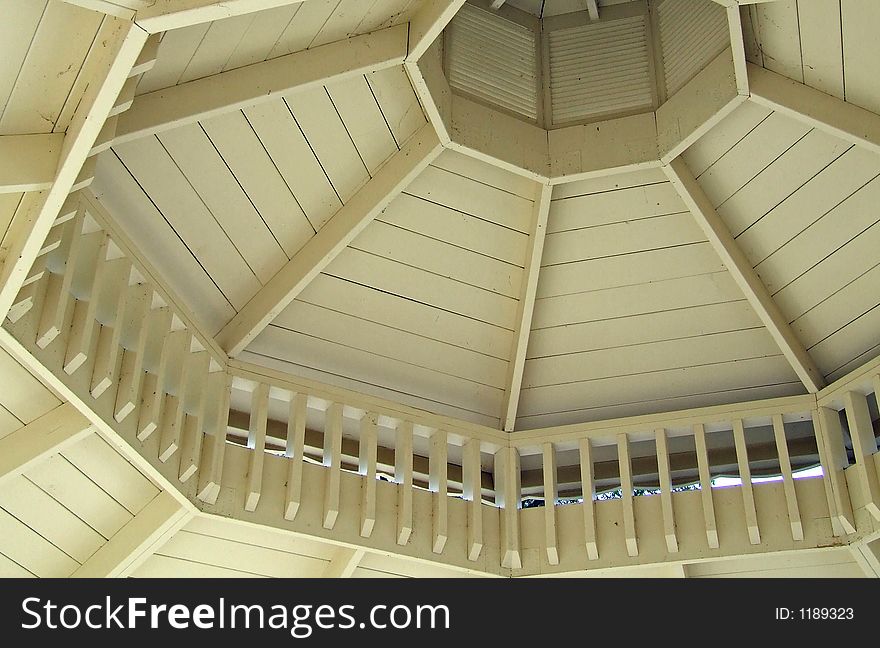 Photo of ceiling of wooden gazebo showing the intricate supports and arrangement of beams. Photo of ceiling of wooden gazebo showing the intricate supports and arrangement of beams.