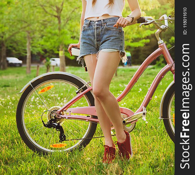 Beautiful woman with bicycle on the meadow in the park. Closeup picture. Beautiful woman with bicycle on the meadow in the park. Closeup picture