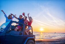 Young People Having Fun In Convertible Car At The Beach At Sunset. Royalty Free Stock Photo
