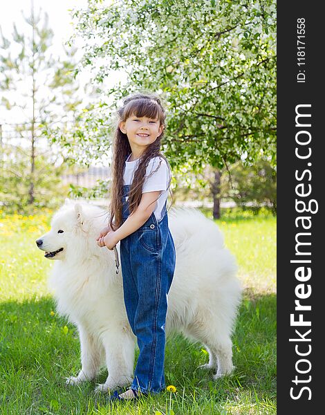 A beautiful 5 year old girl in jeans hugs her favorite dog during a summer walk. A beautiful 5 year old girl in jeans hugs her favorite dog during a summer walk.