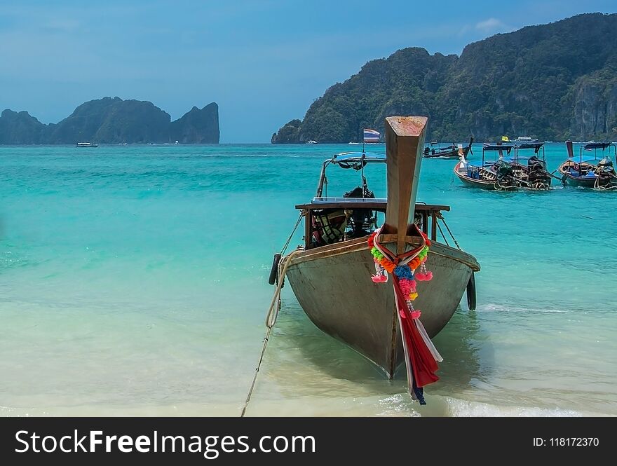 Long tail taxi boat on turquoise water with mountains background on Andaman island. Long tail taxi boat on turquoise water with mountains background on Andaman island.
