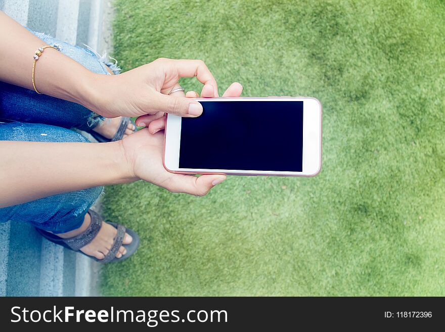 Girl,woman looking at the smartphone sitting in park.