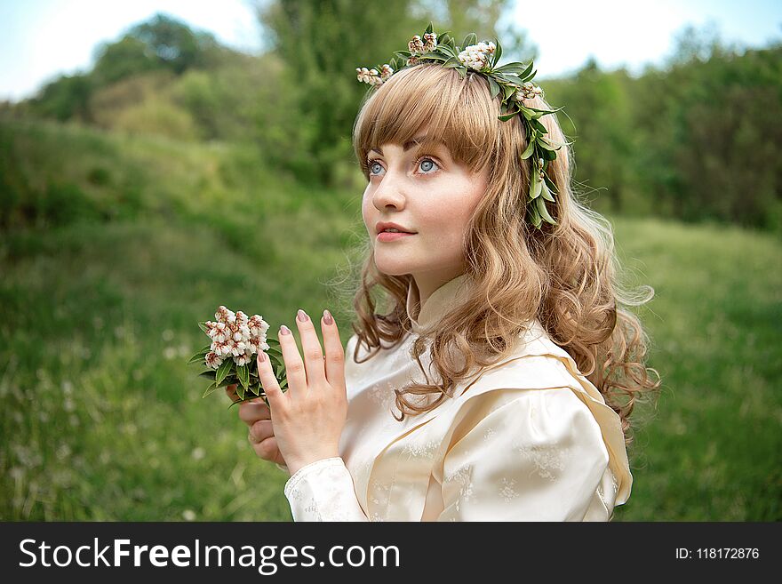 Portrait of beautiful lady with wreath on head in green field outdoors. Vintage colours shot.