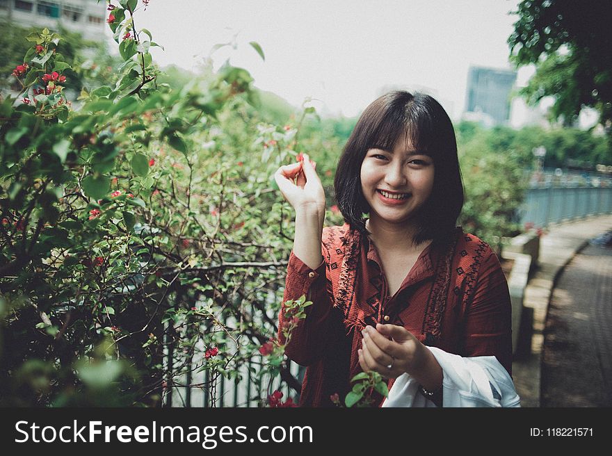 Woman Wearing Red Collared Shirt Standing Beside Plant