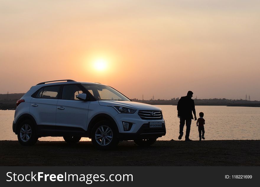 Silhouette of Man and Child Near White Hyundai Tucson Suv during Golden Hour