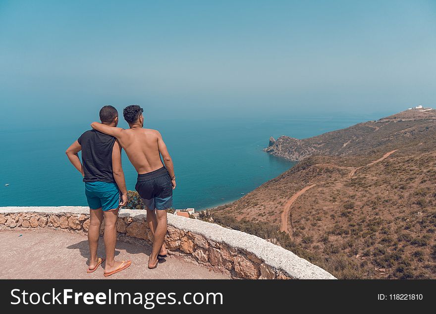 Two Man Standing on Mountain Cliff With Ocean View