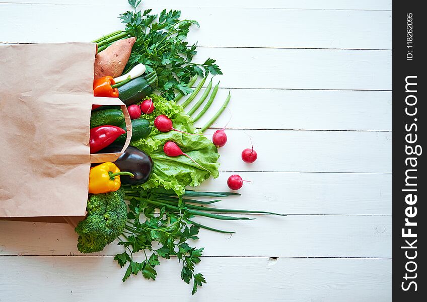 Fresh organic vegetables on white wooden boards background, top view. Healthy food concept.