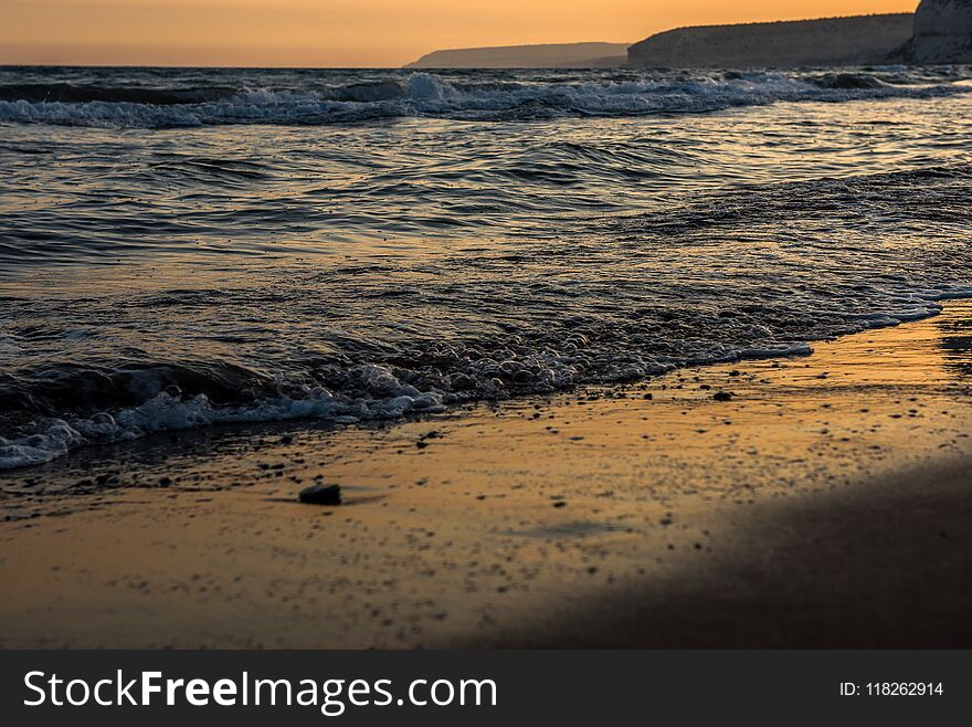 Waves approaching sandy beach during golden sunset