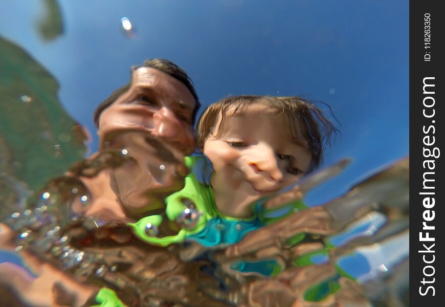 Underwater view of a father and her daughter with distorted face