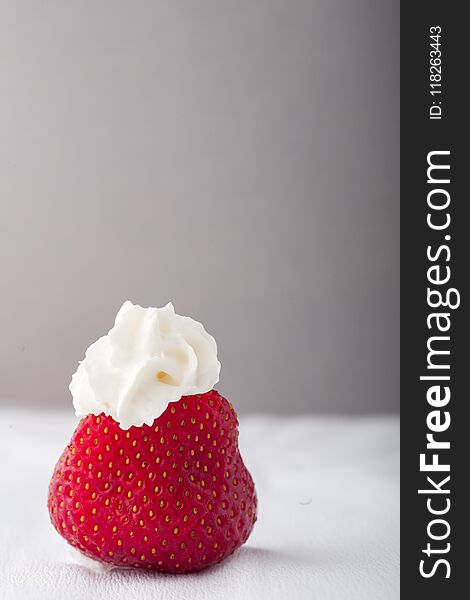 Single Strawberry With Whipped Cream On A White Grey Background.