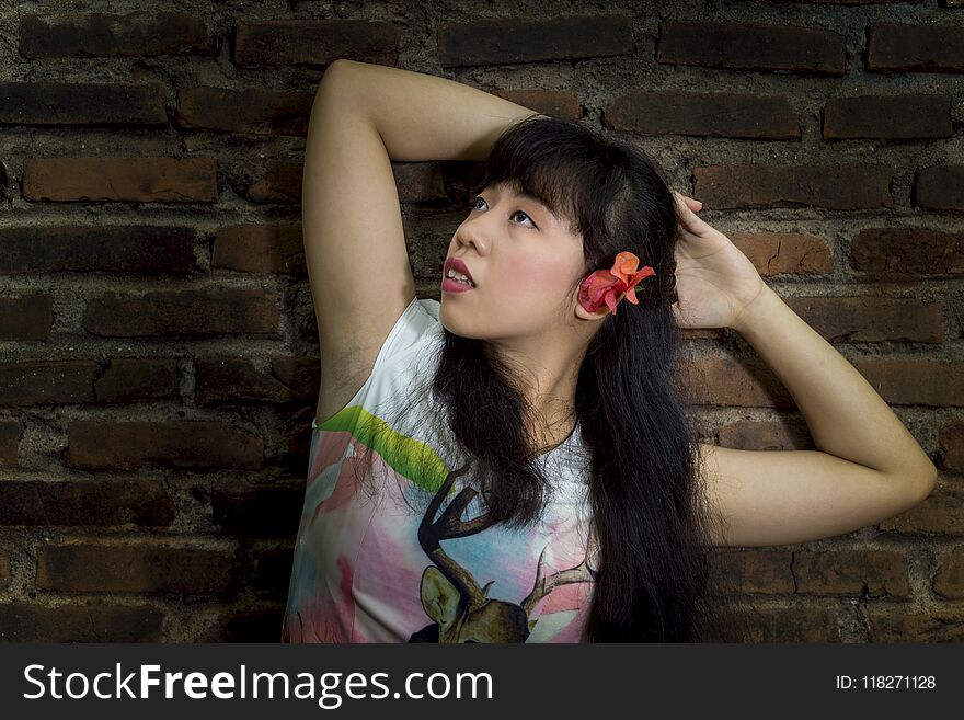 Asian young girl standing by an old brick wall