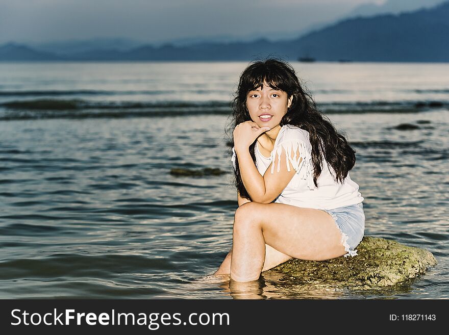 Girl sitting on a rock in the evening sea. Girl sitting on a rock in the evening sea