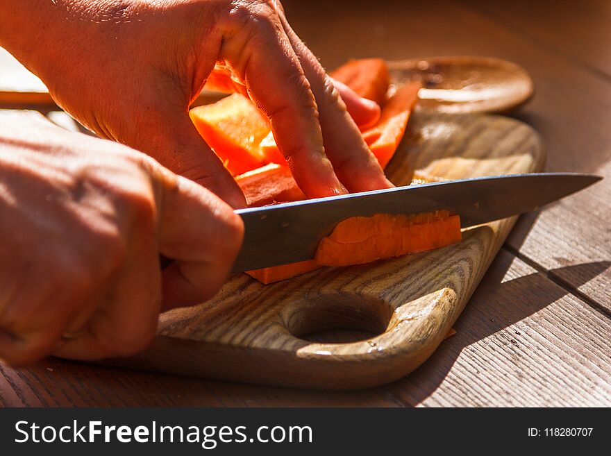 Slicing cooking carrots on wooden cutting board. Slicing cooking carrots on wooden cutting board