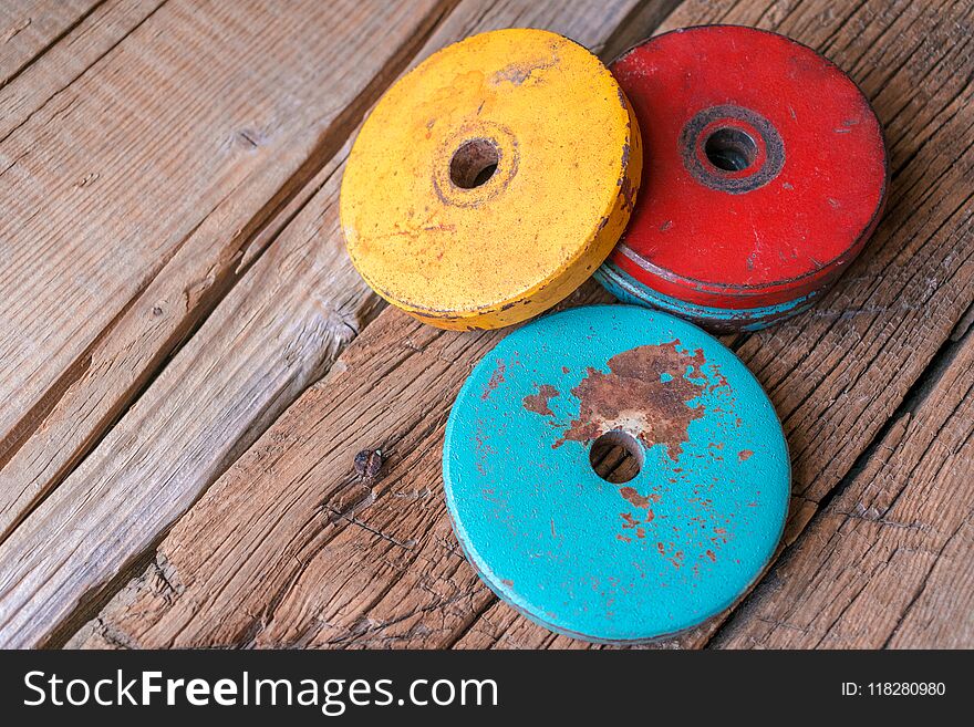 Photo of colored old pancakes for dumbbells. On a wooden background. Photo of colored old pancakes for dumbbells. On a wooden background.