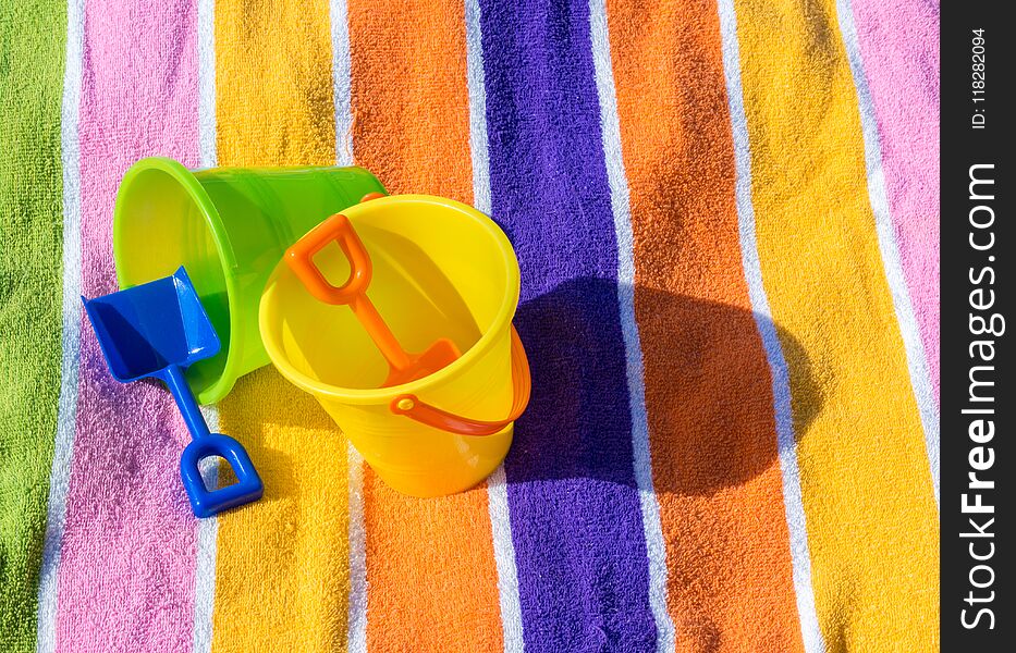 2 child`s sand pails and shovels on a striped beach towel