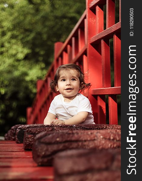 Baby Wearing White Crew-neck Shirt Beside Red Wooden Fence
