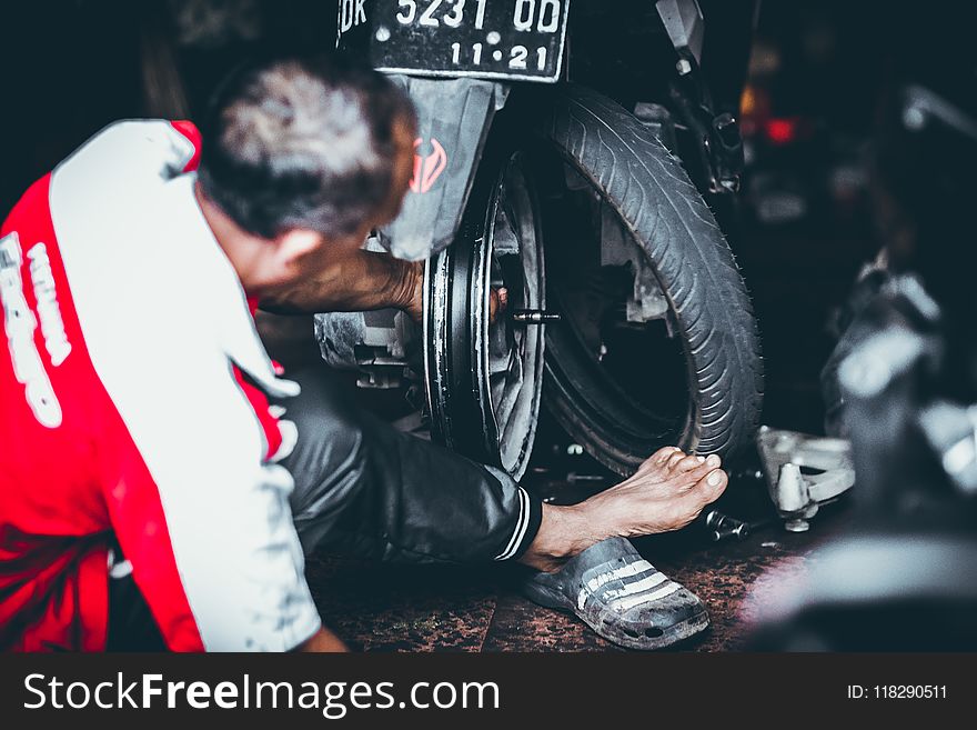 Man Changing a Rear Tire of a Motor Scooter