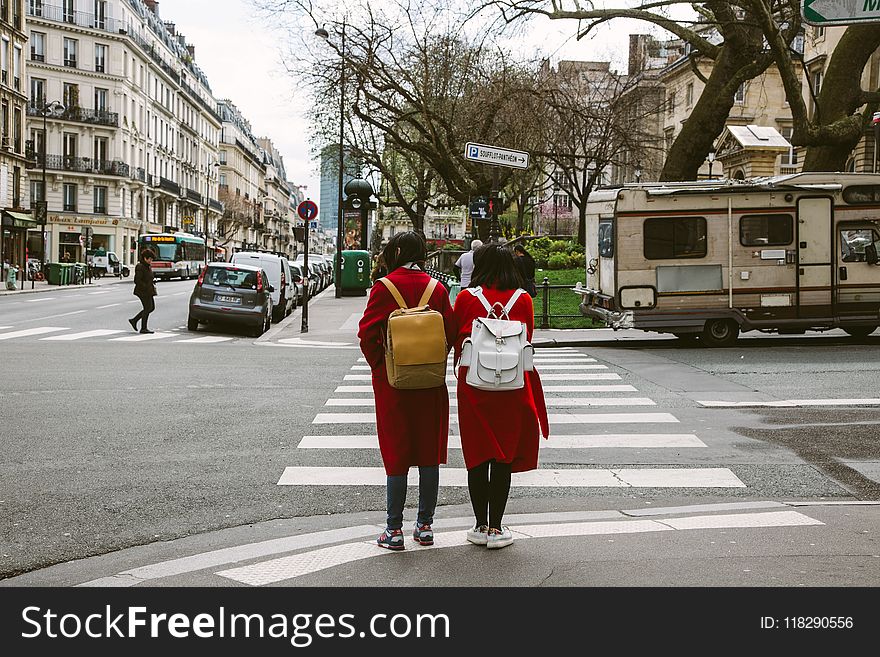 Two Women Wearing Red Coats With Backpacks