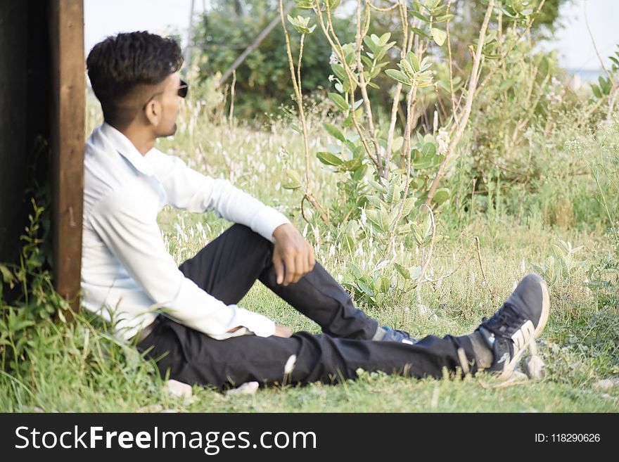 Man In White Long-sleeved Top Sitting On Green Grass