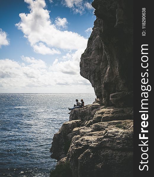 Two People Sitting By The Cliff