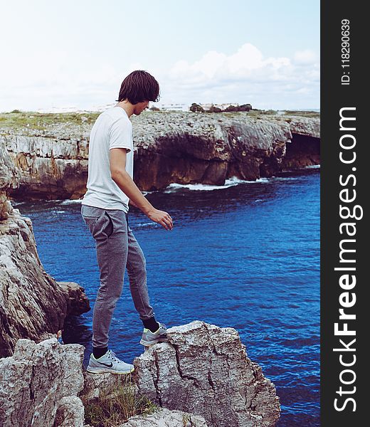 Man In White Shirt And Grey Pants Standing On Cliff
