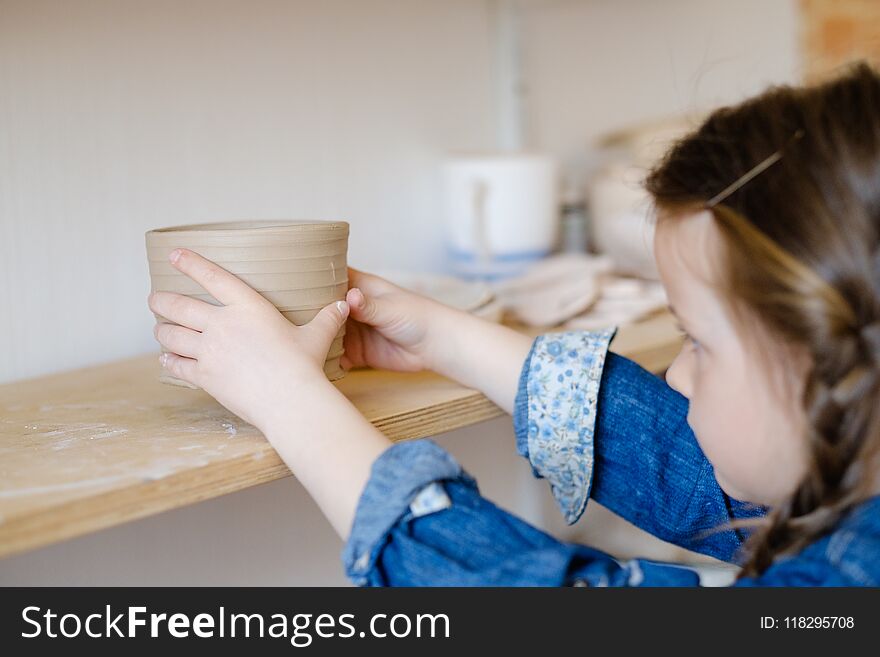 Child hobby. creative pottery leisure. artistic kid upbringing. little girl putting a handmade clay jug on a shelf. Child hobby. creative pottery leisure. artistic kid upbringing. little girl putting a handmade clay jug on a shelf