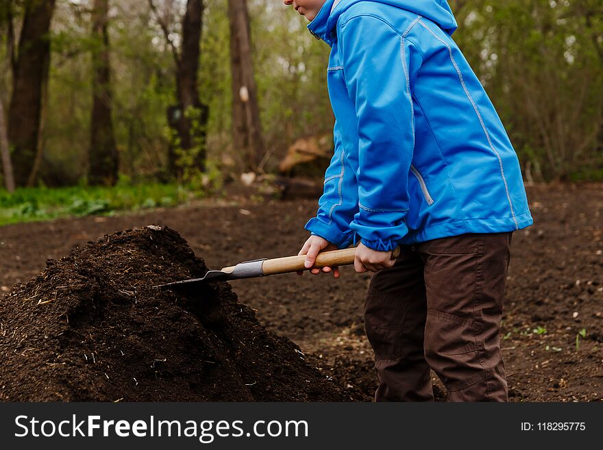 The child is gaining ground shovel in the garden. The child is gaining ground shovel in the garden