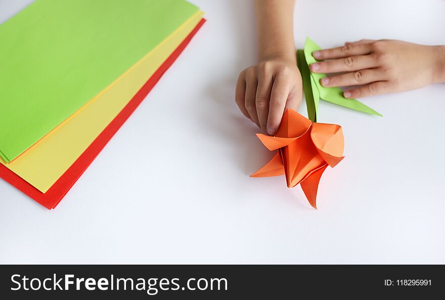 Children`s Hands Do Origami From Colored Paper On White Background. Lesson Of Origami