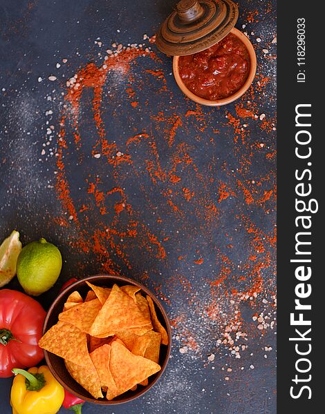 Tortilla nacho chips in a bowl. salsa sauce in a dipping dish. food spices mix background. salty spicy crunchy slices. powdered pepper and salt condiments. Tortilla nacho chips in a bowl. salsa sauce in a dipping dish. food spices mix background. salty spicy crunchy slices. powdered pepper and salt condiments