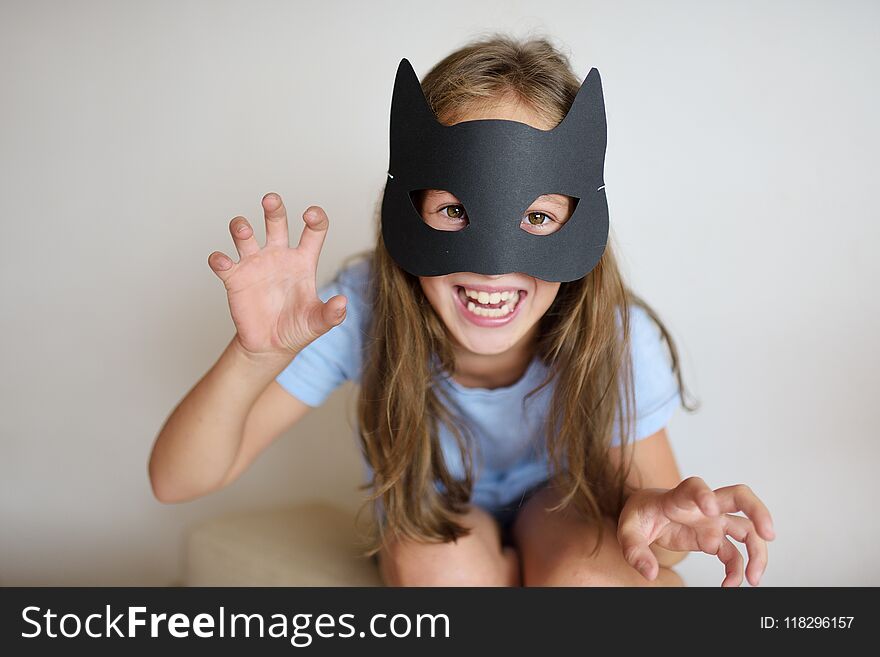 The girl plays in a self-made mask of black cat for Halloween