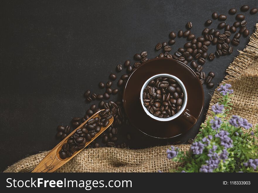 Cup of coffee on black table. Top view mockup a cup of coffee with coffee beans and hemp sack on the black stone.